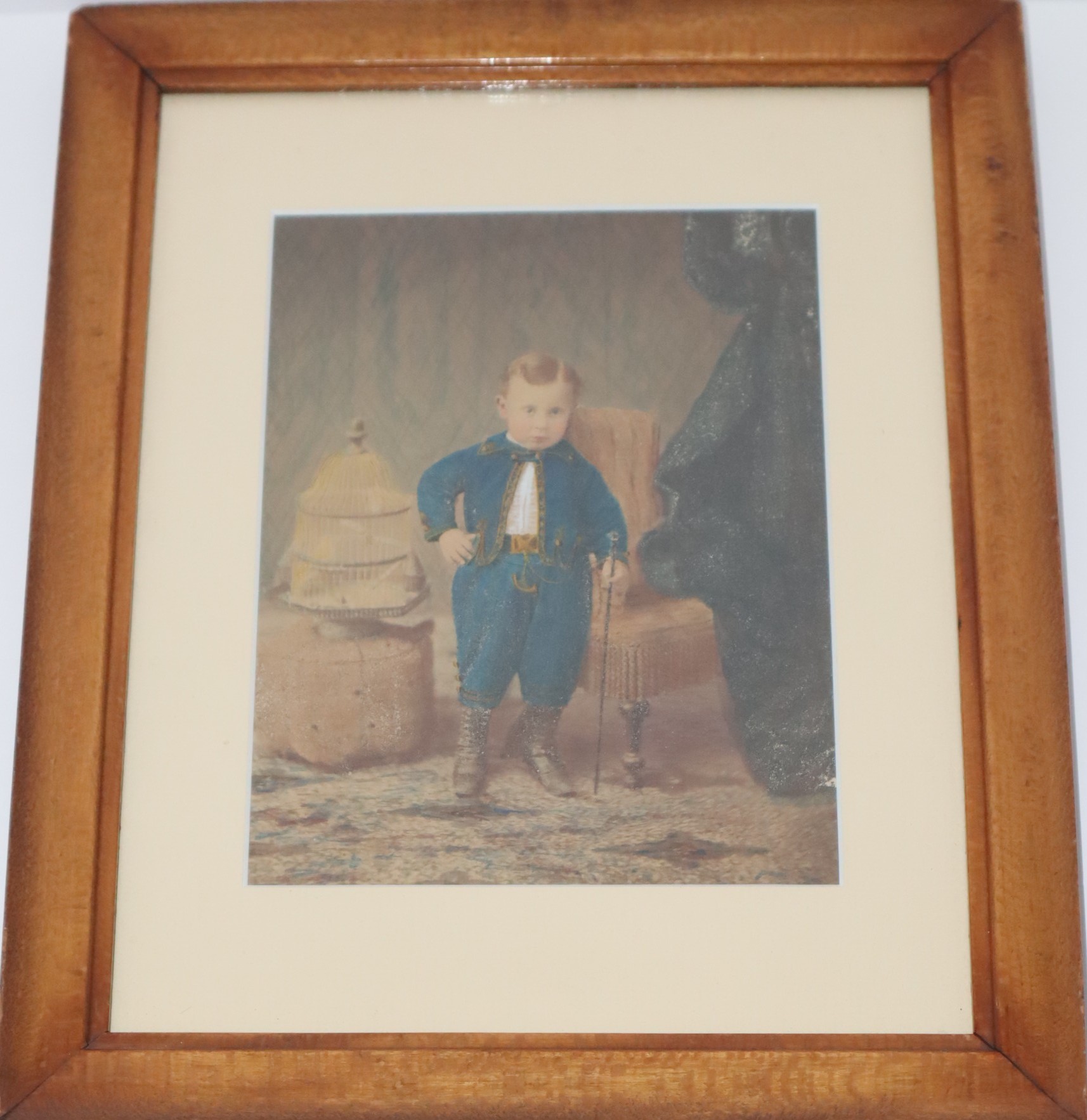 Framed and Matted Colorized 19th Century Photo of Boy in Jaunty Velvet Uniform, Holding a Crop, a Birdcage to His Right